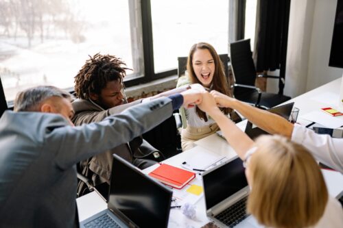 Grupo de pessoas sentadas ao redor de uma mesa de trabalho.