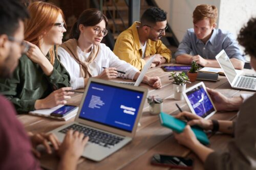 Equipe reunida em mesa com computadores.