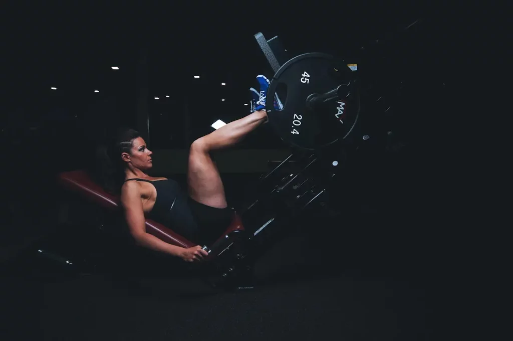 Mulher em academia fazendo exercícios no leg press