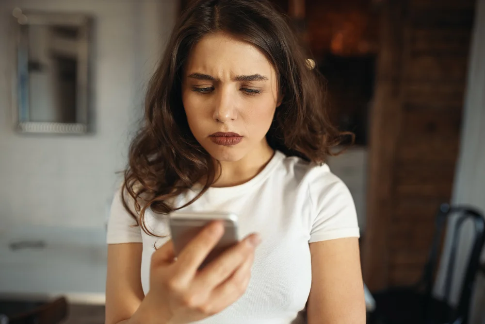 fomo: mulher adulta segurando um smartphone enquanto passa pelo fenômeno explicado no texto